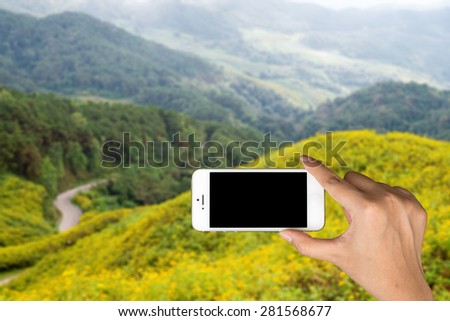 Smart phone in the hands of women and mountains in the background