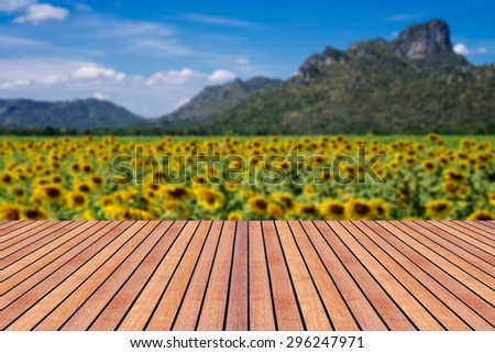Vintage wooden board table in front of summer landscape. Perspective wood floor over blur sun flower with bokeh background - can be used for display or montage your products. Blurred background.