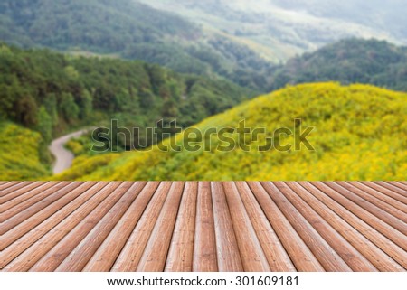 Vintage wooden board table in front of mountain landscape. Perspective wood floor over blur yellow flower with bokeh background - can be used for display or montage your products. Blurred background.