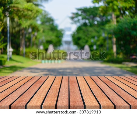 Wooden board empty table in front of blurred background. Perspective brown wood with  people activities in park - can be used for display or montage your products. spring season. vintage filtered .