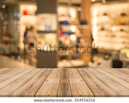 Wooden board empty table in front of blurred background. Perspective brown wood over blur store in mall - can be used for display or montage your products. vintage filtered image.