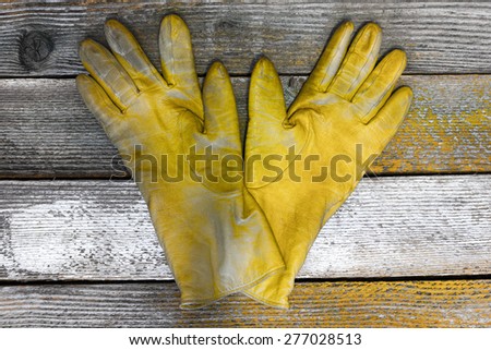 a pair of yellow women\'s leather gloves on the old boards