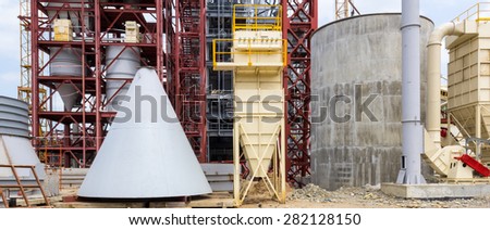 construction of the enterprise for plaster processing, gray steel cone and the mounted details of designs from metal