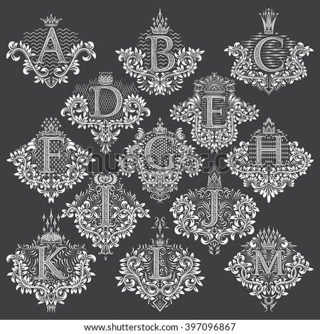 Set of heraldic monograms in coats of arms form. White floral decorative stamps of letters from A to M. Isolated tattoo labels in vintage baroque style.