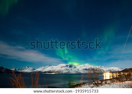 Northern lights, Aurora seen in polar region landscape and fjord mountain over the night sky in Norway