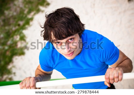 Toned picture of man on horizontal bar in the middle of his pull up