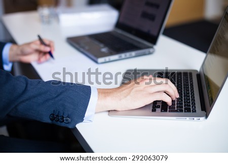 Detail of manager\'s hand typing and working with laptop in the office