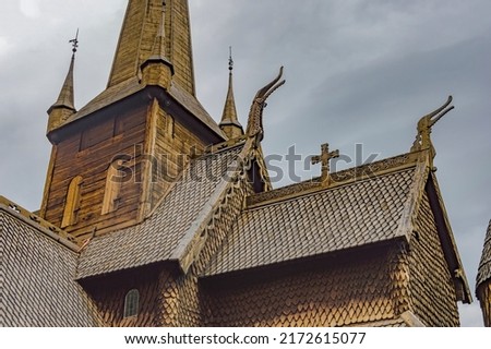 Details of the Lom stave church in Lom Norway: roof carved figures, bell tower windows, dragon heads on the gables, crosse atop the roofs. Dramatic cloudy sky Stock fotó © 
