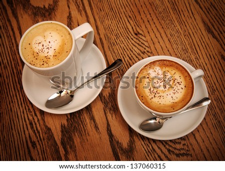 two cups cappuccino and latte on wooden table in cafe