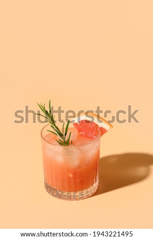 Grapefruit juice garnish rosemary sprig on color beige background. Mocktail Paloma. Close up. Vertical format.