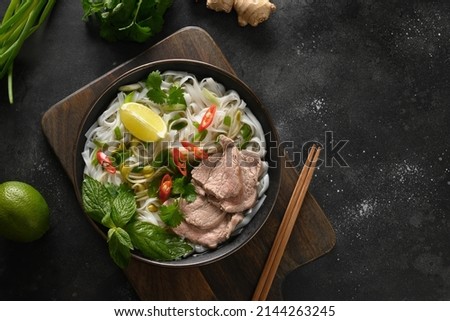 Pho Bo soup with beef, rice noodles, lime, chili pepper in bowl on black background. Vietnamese and Asian cuisine. Stok fotoğraf © 