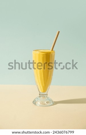 Foto Bild Mango-Smoothie auf blauer Farbe. Sommerliches Getränk. Mangoshake mit Strohhalm