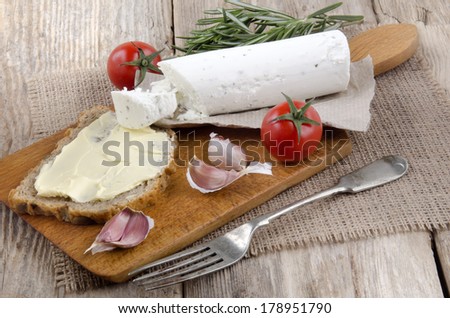 wooden board with bread, soft goat cheese and tomato