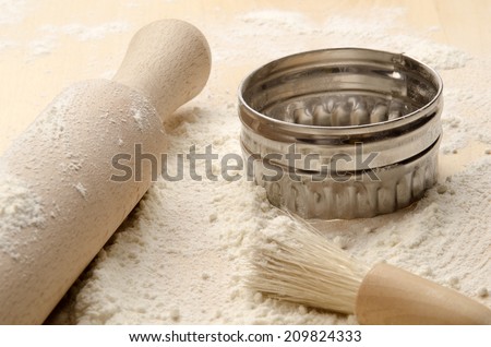 floured baking board with rolling pin, cookie cutter and brush