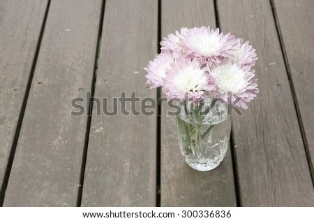 Rustic bunch of pink chrysanthemum flowers in a kitchen glass on a timber background