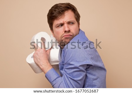 Greedy caucasian man holding several rolls of toiler paper on his hand hiding it from other people. Panic because of coronavirus situation. Photo stock © 