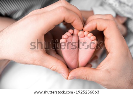 Feet of the newborn in the hands of mom close up. Heart. Mom and her child. A beautiful conceptual image of motherhood.