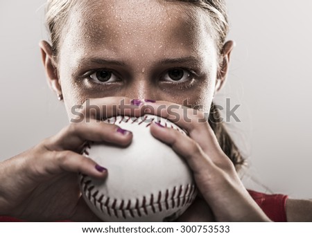 Edgy softball girl with sweat looking from behind a softball