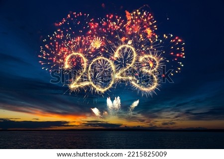 Photo of Happy New Year 2023. Beautiful creative holiday web banner or flyer with red fireworks and Golden sparkling number 2023 on blue sky  over sea