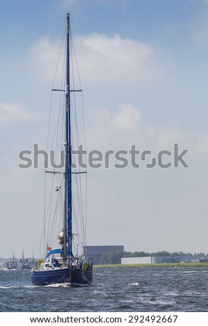 Port of Amsterdam, Noord-Holland/Netherlands - June 27-06-2015 - Blue english sailing yacht is sailing at the Noordzeekanaal. Blue cloudy sky at the background.