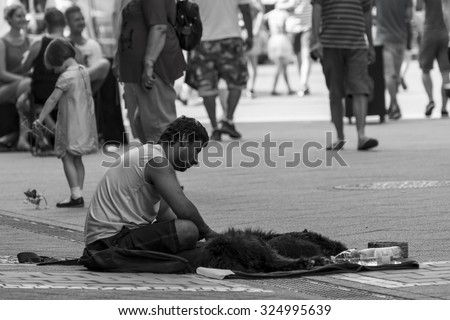 Budapest,Hungary - July 26-07-2015 - Poor homeless men is sitting on the street next to his dog. Behind the men a little girl is playing with her puppet dog toy.