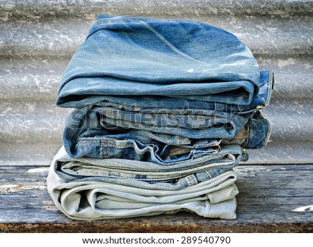 Pile of Old Jeans on Old Wooden Table - Texture Background