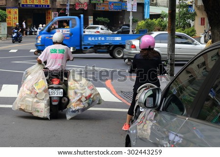 New Taipei City, Taiwan - August 1, 2015: A man riding a motorcycle carrying two big bags of recycling garbage.