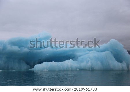 Bright Blue Iceberg Floating in the Jokulsarlon Glacier Lagoon on the Southern Coast of Iceland and some Reflection Imagine de stoc © 