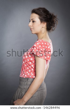 young caucasian female in red blouse isolated on grey background. Fresh natural makeup, big brown eyes, long lashes, gentle soft pink lipstick. Tied romantic hairstyle.