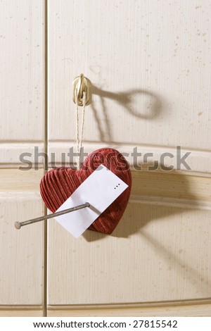 Wooden heart with nail hang on door of white  wardrobe. You can write on white note \