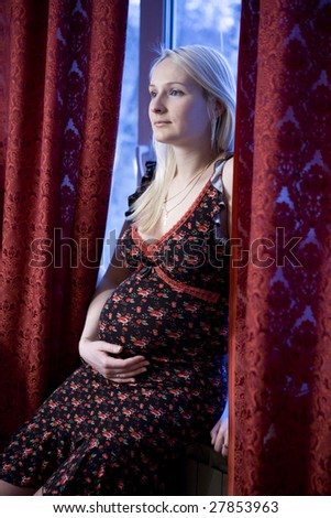 attractive pregnant blond  serious woman at window