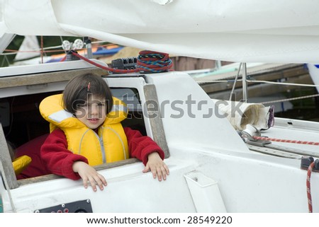 Little cute girl in life jacket on yacht. Summer time