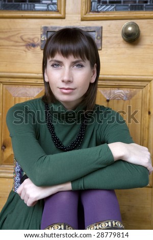 portrait attractive brunette pensive woman wearing green blouse sitting on doorstep