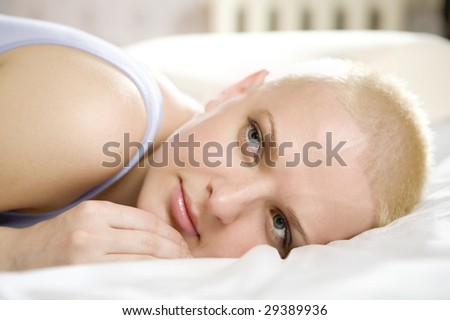 portrait of thoughtful blond bald woman lying on the bed