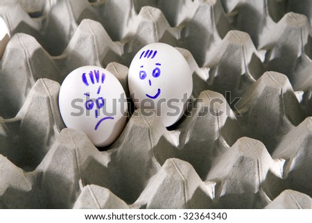 Hen`s eggs in box. One egg cover with drawings. Look like man`s face