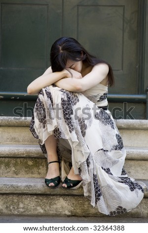 young attractive pensive woman in long dress sitting on stairs. Woman`s problem