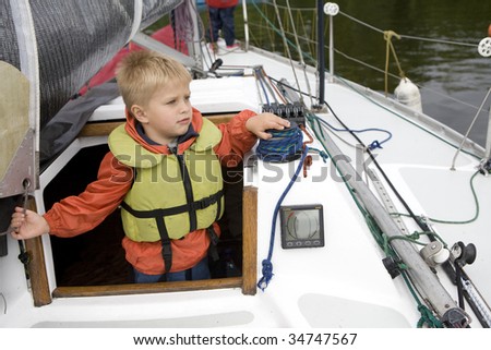 Little cute boy five years old in life jacket on yacht. Summer time