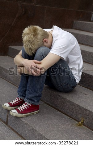 upset  young man sitting on stairs put his head on knees