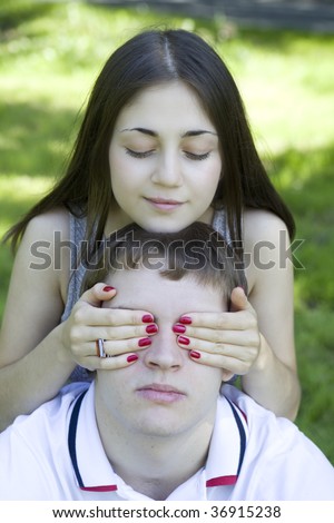 young happy couple.  Girlfriend close man`s eyes by hands. Who is it? guess who?