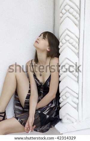 Smoking girls sitting at a white wall and looked at the sky