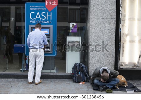 LONDON, UK - JULE 29 2015: Street beggar with dog begging for money near cash mashine. London. UK