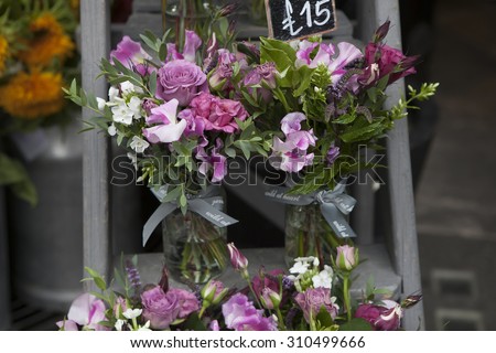 bouquet of Sweet pea, Lathyrus odoratus, flowers in a purple vase standing on wooden grey steps