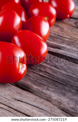 Tomatoes bunch shot on wood top and portrait view in a left corner with negative space