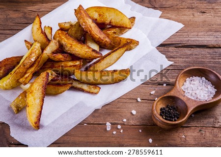 potato wedges on cooking sheets with salt and pepper on wood shot at an angle