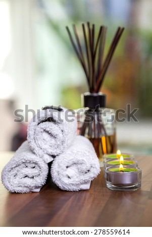 towels, candles, hot stones and scent sticks on wooden background shot front on hot stones on top of towels candles n a side
