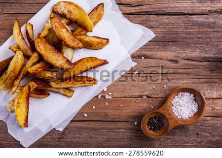 potato wedges on cooking sheets with salt and pepper on wood shot from above