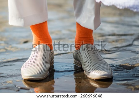funny orange socks as part of the groom\'s suit. White pants and shoes