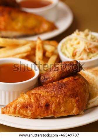 Roast chicken quarter breast with french fries, cole slaw salad and bbq sauce on the side. Shallow depth of field.