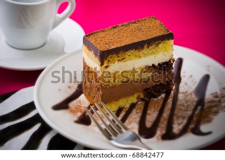 Creamy chocolate mousse cake on a white plate with a pink background. Added vignetting and very shallow depth of field.
