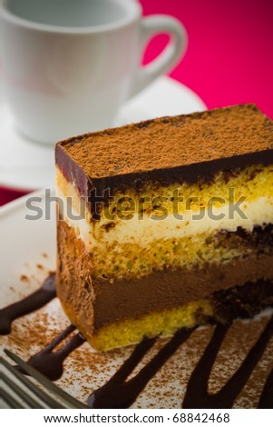 Creamy chocolate mousse cake on a white plate with a pink background. Added vignetting and very shallow depth of field.